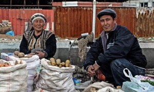 Nel bazar di Osh, Kyrgyzstan, un'anziana signora e suo figlio vendono alcune patate e delle verdure