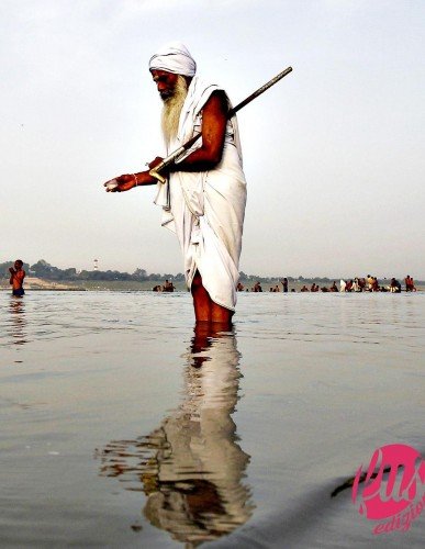 A Sadhu or a Hindu holy man offers milk to the waters of holy ri