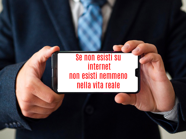 Cellulare tenuto da due mani con la scritta Se non esisti su internet non esisti nemmeno nella vita reale