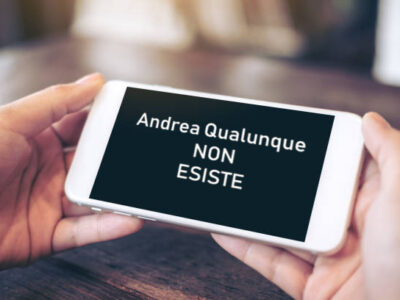 Cellulare tenuto da due mani con la scritta Andrea Qualunque non esiste