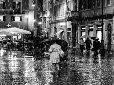 Foto in bianco e nero di una ragazza, di spalle, sotto la pioggia